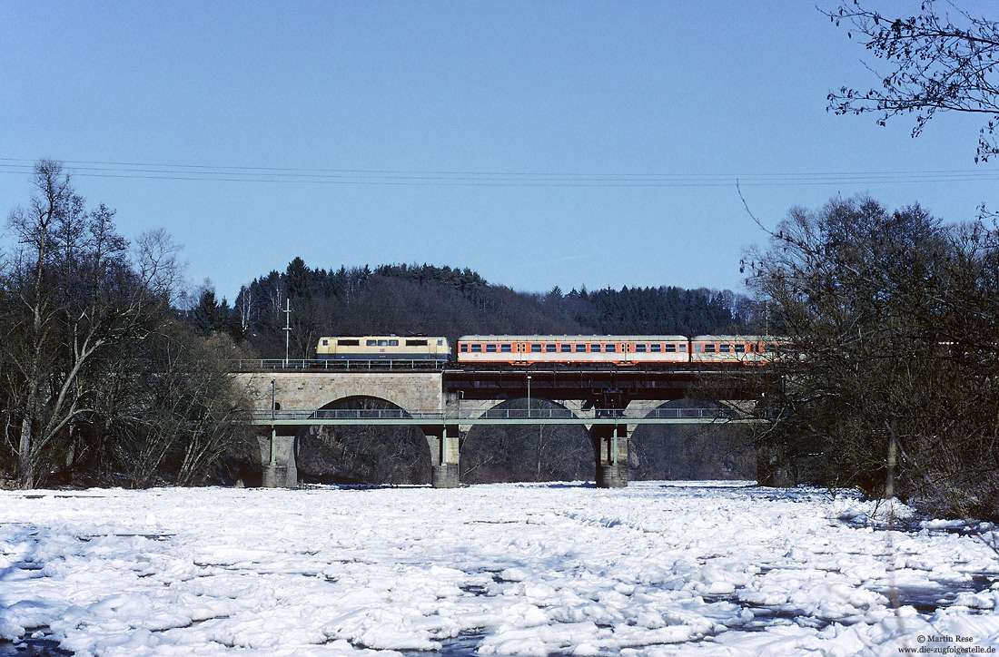 111 013 in ozeanblau/beige mit CityBahn-Wagen als S12 auf der Siegbrücke bei Schladern mit Eis auf der Sieg