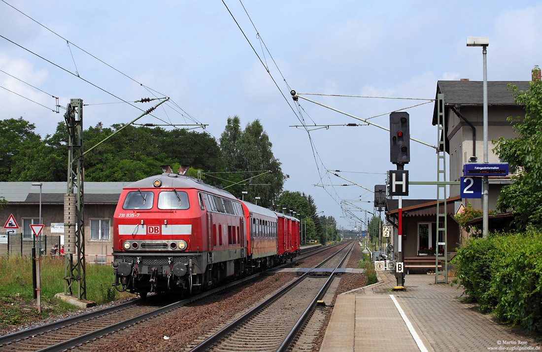 Abschlepplokomotive 218 835 in verkehrsrot mit Hilfsgerätewagen am Haltepunkt Glaubitz