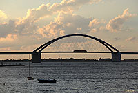 Die auch als „Kleiderbügel“ bezeichnete Fehmarnsundbrücke ist nicht nur das Wahrzeichen von Fehmarn, sie stellt auch die einzige feste Verbindung zum Festland dar. Am Abend des 31.7.2013 überquert die RB21778 (Lübeck - Puttgarden) das Bauwerk.
Einen Gruß noch einmal an unsere Gastfamilie, besonders am Jannik, Ben und Neele …