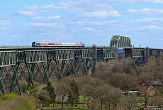 Am Nachmittag des 3.4.2017 poltert der RE11021 (Westerland – Hamburg Altona) über die Hochbrücke bei Hochdonn. Da nicht ausreichend Steuerwagen verfügbar stehen, werden einige Züge im „Sandwichbetrieb“ (jeweils eine Lok an jedem Zugende) gefahren. So war der RE11021 an diesem Tag mit der 245 201 und 245 206 bespannt.