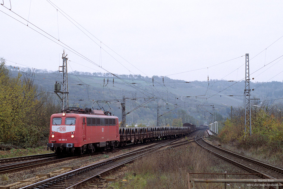 140 001 in orientrot bei der Einfahrt in den Bahnhof Ehrang Gbf