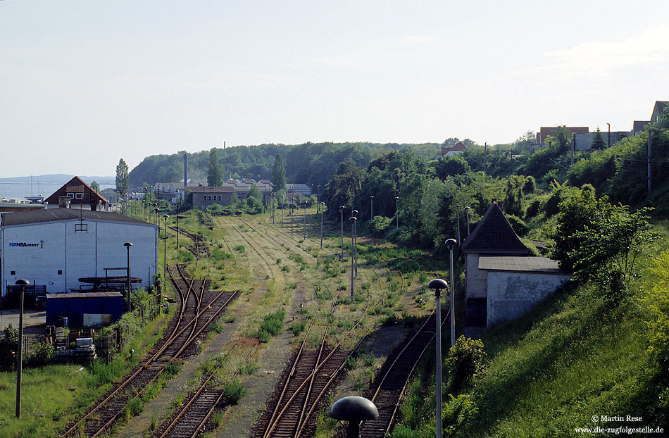 Nach Um- bzw. Neubau des Bahnhofs Sassnitz Fährhafen am Güterbahnhof Mukran Anfang 1998 wurde der Bahnhof Sassnitz Hafen stillgelegt. Am 3.6.1999 bot sich ein trostloses Bild der brach liegenden Bahnanlagen. Rechts ist die ehemalige Strecke nach Sassnitz zu sehen, welche auf einer Strecke von zwei Kilometern einen Höhenunterschied von fast 35 Meter zu überwinden hat!.

